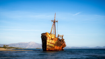 A striking image of a weathered shipwreck standing against a clear blue sky, showcasing the beauty...