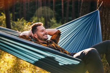 Man camping in forest resting in hammock enjoying vacation in nature