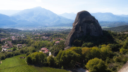 A breathtaking view showcasing a prominent rock formation surrounded by lush greenery and mountains, capturing the serene beauty of nature in the background scenery.