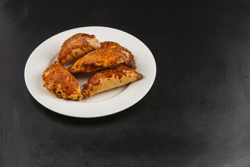 Delicious pumpkin-filled pastries arranged on a white plate on black surface