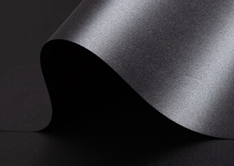 Black paper background with a smooth, glossy texture and metallic, reflective finish. Elegant,...