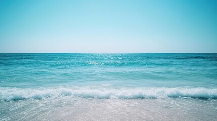 Gentle ocean waves ripple beneath a calm, clear sky, creating a serene and tranquil seascape.