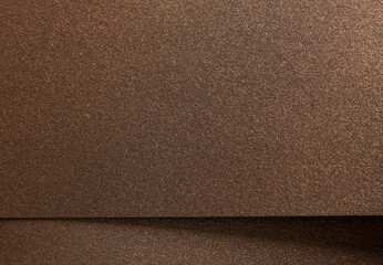 Fototapeta premium Warm gold and bronze paper background with a pearlescent, metallic texture and subtle shimmer. The reflective light and shadow create an elegant, luxurious design, perfect for premium designer paper.