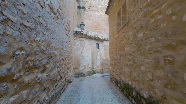 Narrow alley with very old stone walls and medieval arches in the streets of Baeza, Jaen, Spain.