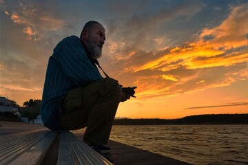 Fototapeta premium A man sitting on a pier at sunset