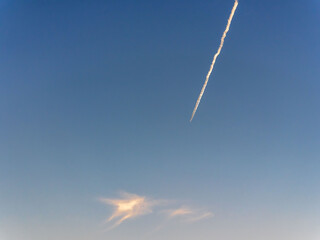 春の夕日の空に飛行機雲03