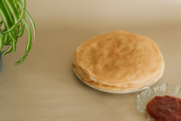 a stack of thin golden pancakes on a white plate on a light background. an empty space for the text. layout of an advertising banner for a cafe