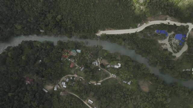 Drone flies north over Cahabon River and the bridge on partially cloudy day in Semuc Champey, Guatemala