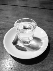 A shot glass of alcohol and pickles on a plate