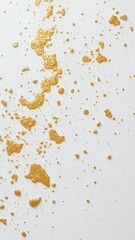 Delicate gold paint splatters on white surface, glitter, paint spills