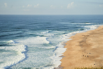 A breathtaking aerial view of a sandy beach and crystalclear ocean waters from a majestic cliff...