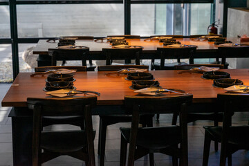 A cozy and atmospheric hot pot dining space invites guests to enjoy a warm, intimate meal in a dimly lit setting. Soft, ambient lighting casts a gentle glow over the wooden tables, where steaming