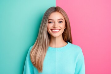 Fototapeta premium Confident young woman with long brown hair smiling while standing in front of a bright turquoise backdrop, reflecting self assurance and a positive attitude
