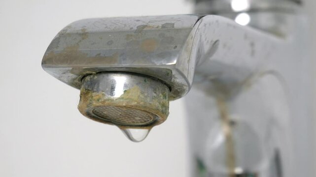 Water is dripping from a damaged faucet. The old faucet was covered with lime scale due to poor water quality and hard water. Useless use of water. Plumbing problems. 4k