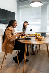 Fototapeta premium Businesswomen having breakfast and working on laptop in hotel room