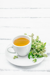 Lemon balm tea on white wooden background. Fresh edible herbs, trendy drink. Organic healthcare