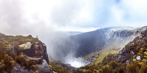 Misty view of waterfall in lush mountainous landscape