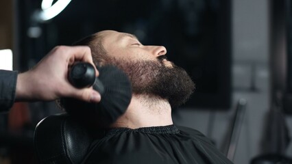 Skilled barber brushing client's beard, providing precise grooming within elegant barbershop setting, highlighting professional hair styling expertise