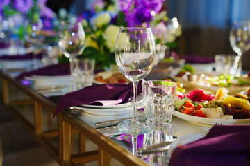 Beautiful festive table setting with flowers and purple napkins. 