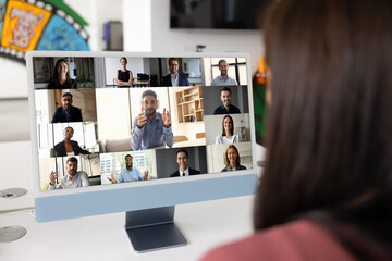 Female employee using computer screen for video conference chat with diverse colleagues, watching...