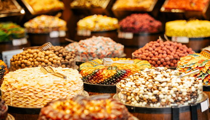 A colorful assortment of dried fruits, nuts, and chocolate treats displayed in wooden barrels at a market. The vibrant arrangement highlights gourmet and artisanal delicacies.