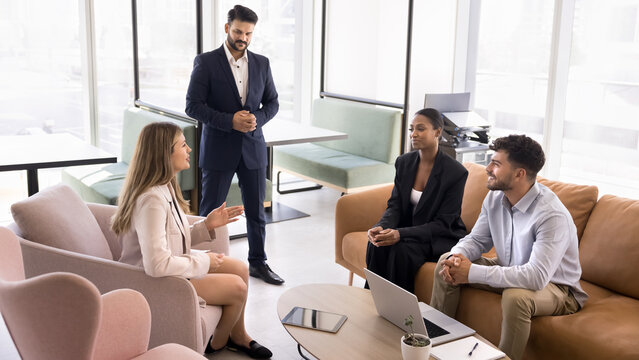 Four multiethnic teammates, met in coworking space to solve business-related matters, discuss performance of joint project or new business opportunity, exploring potential partnerships or cooperation