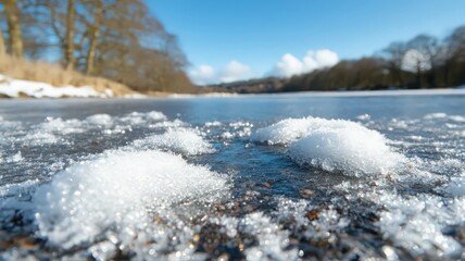 Close Up of Snow on Partially Frozen River Water Under Bright Sunlight