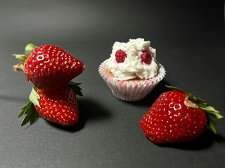 Strawberry and chocolate cupcake with cream on black background