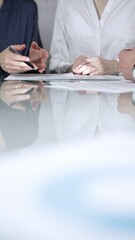 Business people are reviewing contract terms during a meeting, negotiating and making decisions together, vertical close up view. Copy space area