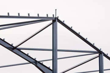 Metal construction, in the photo the structure of the building frame made of metal beams against the background of a gray sky