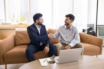 Two young 30s businessmen shaking hands, finish successful business meeting, making profitable...