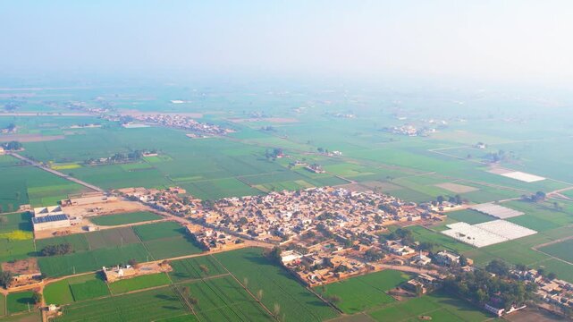 ush green fields and a rural village in Punjab, Pakistan, during winter