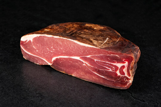 Traditional artisan and handcrafted air-dried Prosciutto offered as close-up on a rustic black board