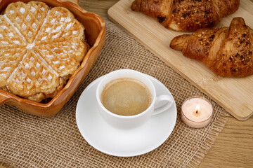 A cup of coffee, waffles and croissants on the table. Breakfast with coffee