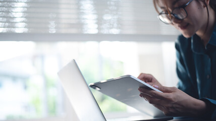 Business woman using digital tablet during working on laptop computer at modern office. Student studying online, e-learning, Freelancer online working, surfing the internet, work from home office