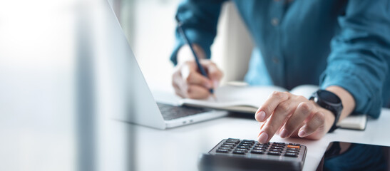 Doing finance, budgeting and tax calculation. Close up woman hand using calculator to calculate...