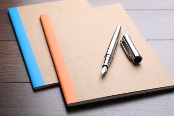 Copybooks and fountain pen on wooden table, closeup