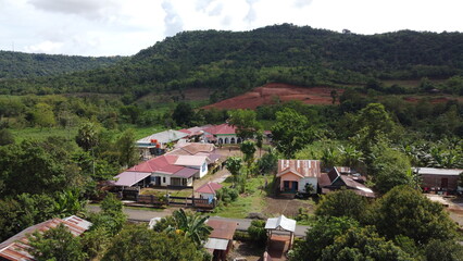 Rural village with red roofed buildings and lush green hills in the background