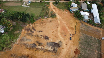 Cleared land with dirt roads and surrounding rural houses