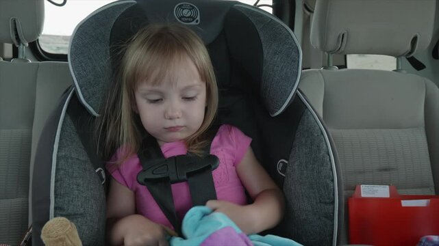 Cute Little Girl Trying to Get settled in her Car Seat