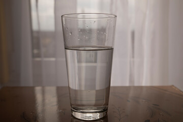 Close-up of a glass cup with clean water. Symbol of vitality, freshness and importance of water consumption.