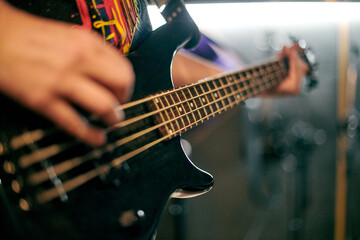 Focused view of musician hand playing bass guitar during performance, highlighting strings and...