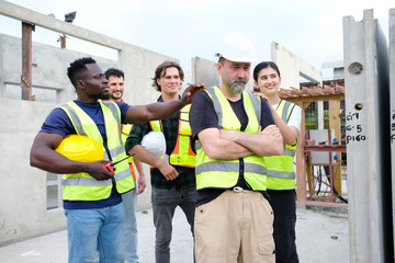 Obraz premium Male engineer and workers standing smiling at construction site.