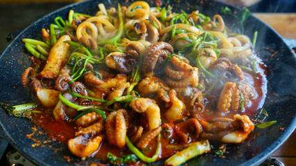 Close up of Korean spicy stir-fried squid on hot iron plate,