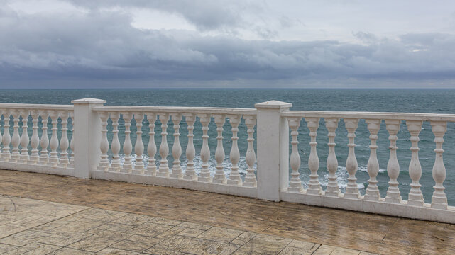 A parapet on the embankment for walking by the sea. Inclement weather on the Black Sea. Thunderclouds and a storm at sea. A recreation area by the sea.