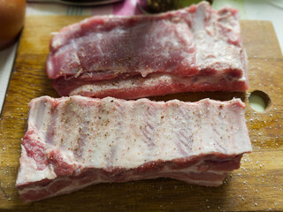 Raw pork ribs pieces sprinkled with spices on cutting board