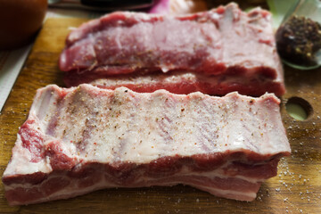 Raw pork ribs with spices on cutting board, front view
