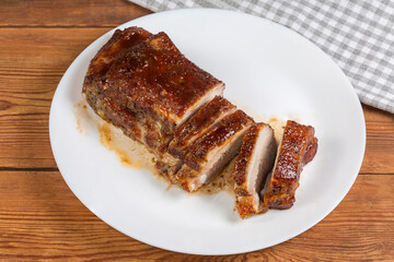 Partially sliced baked pork ribs on dish on rustic table