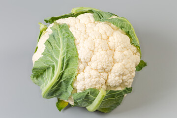 Whole raw cauliflower head on a gray background