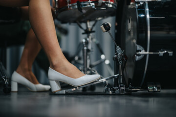 Drummer's foot in white high heels pressing a bass drum pedal. A unique combination of musical...